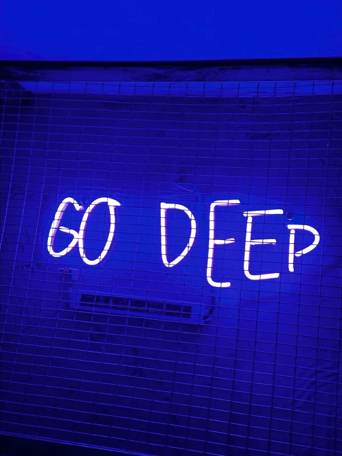 a neon sign that says go deep on a wall